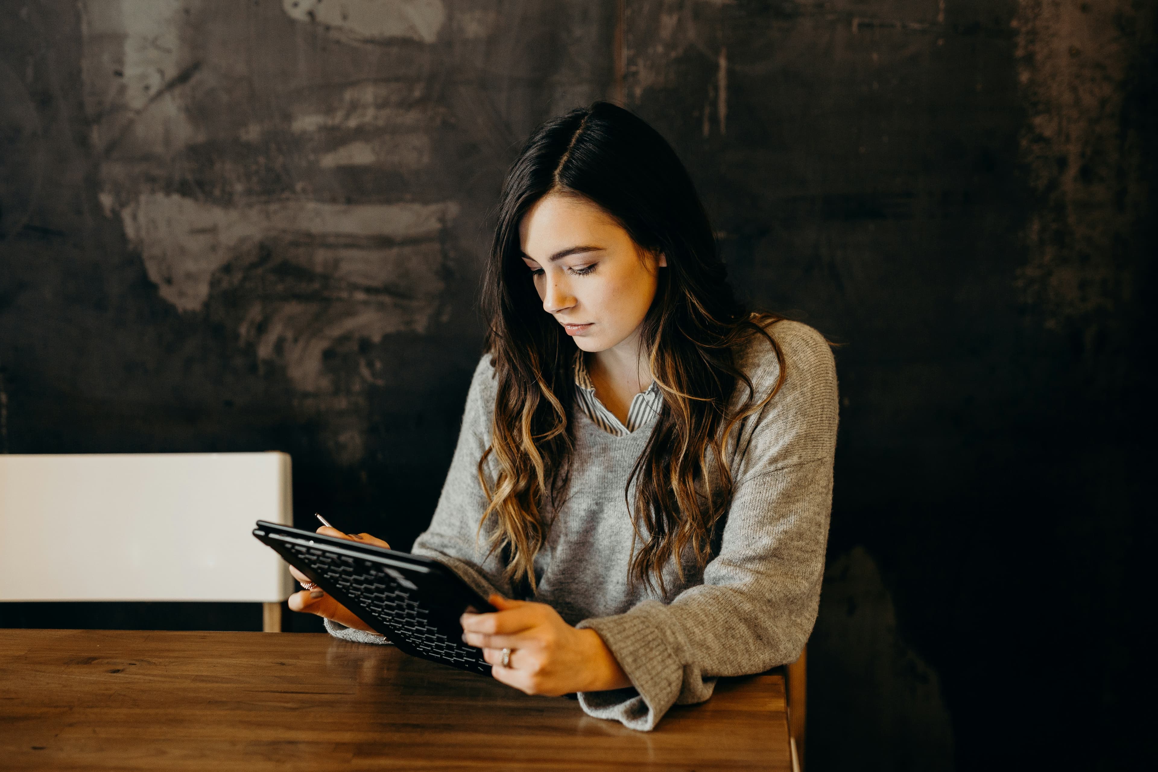 A woman working with a tablet at a desk.