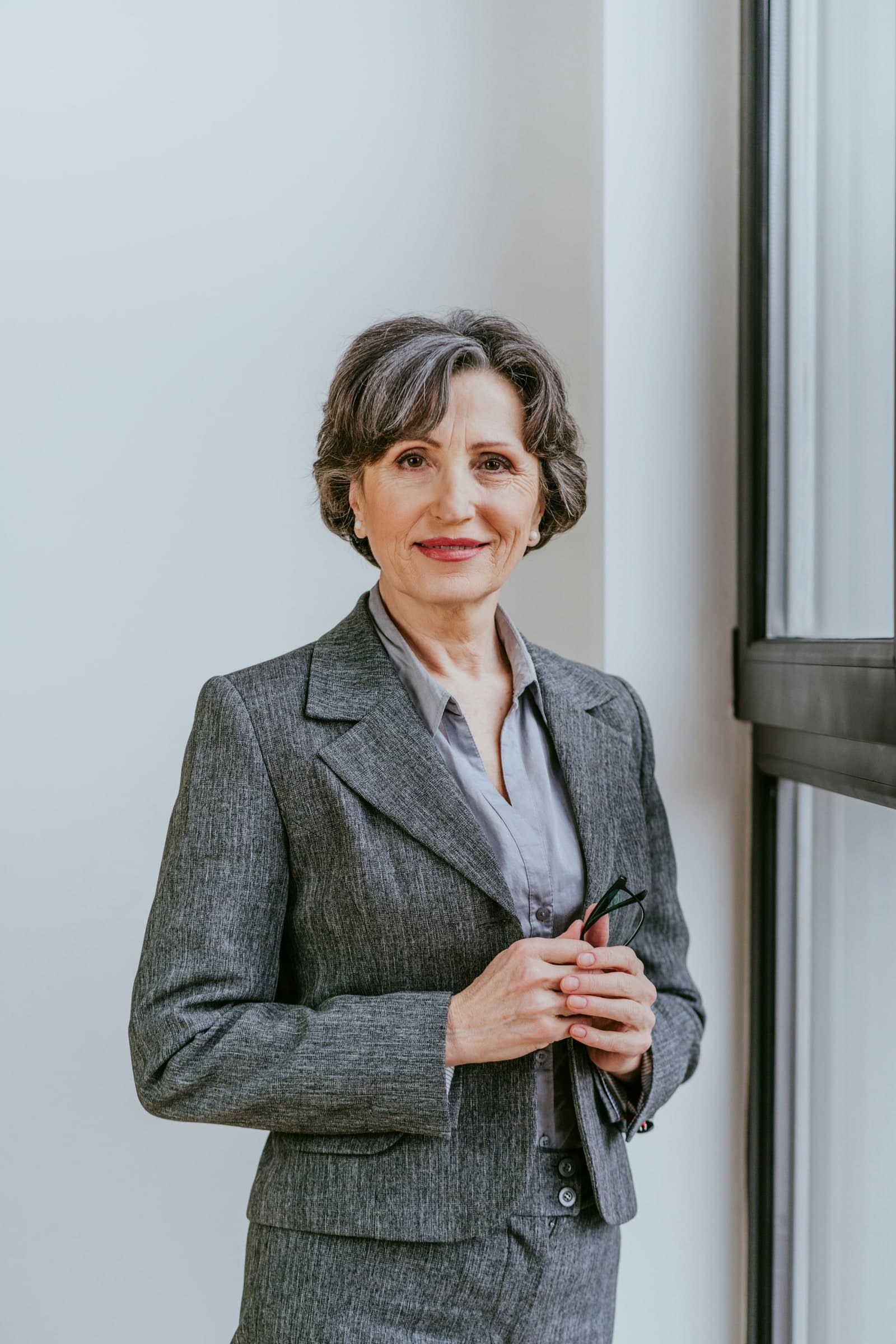 A professional woman standing beside a window in a private diagnostics setting.