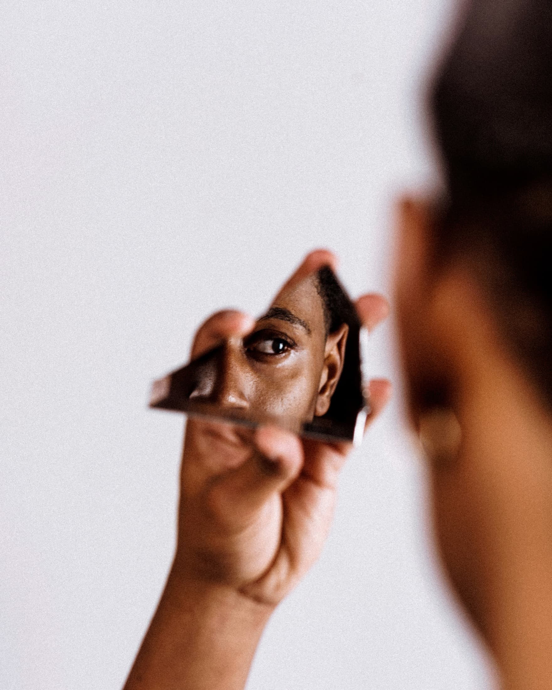 A woman looking at her reflection in a broken mirror.