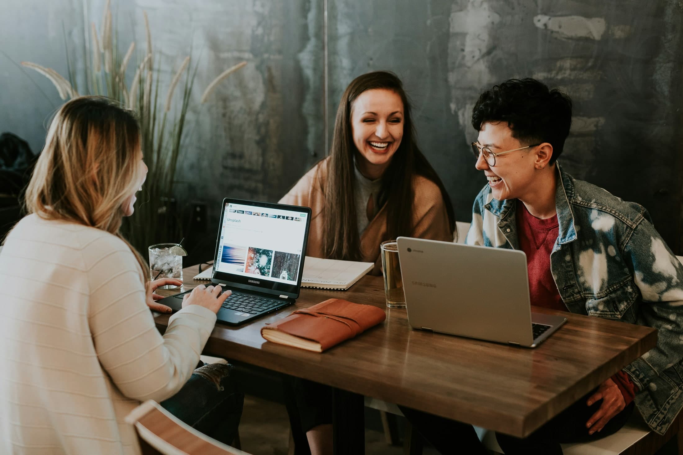 A small group in conversation around laptops and notebooks.