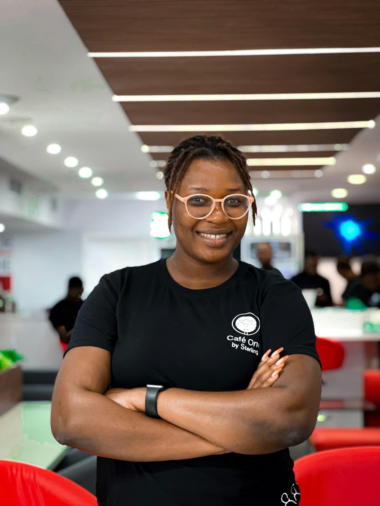 A confident woman standing in a cafe workspace.